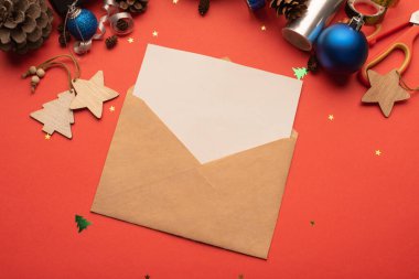 İçinde boş bir kağıt ve kırmızı arka planda Noel süslemesi olan el işi zarf.