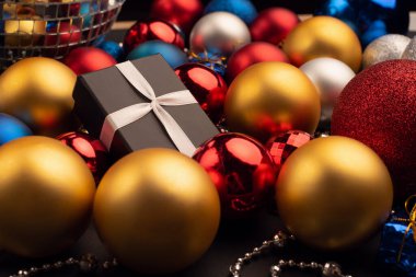 Noel topları arasında farklı renk ve boyutlarda bir hediye kutusu.