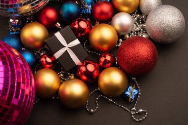 Noel topları arasında farklı renk ve boyutlarda bir hediye kutusu.
