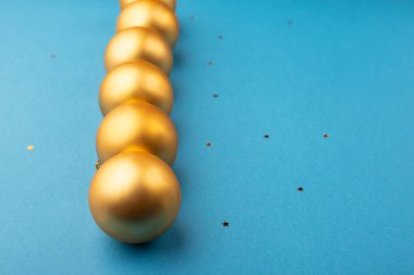 Yıldızlı açık mavi arka planda altın Noel topları