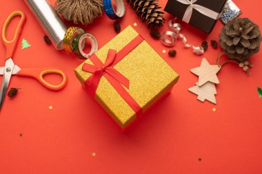 Altın bir hediye kutusu ve eğri büğrü bir Noel kompozisyon. Parlak kırmızı arkaplan.