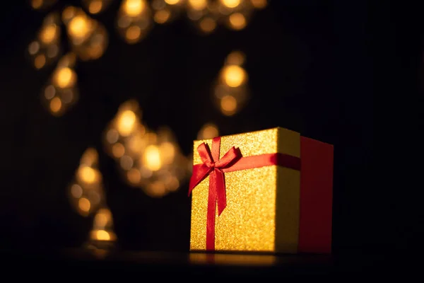 Eine Geschenkschachtel Auf Dunklem Hintergrund Mit Bokeh Lichtern Einer Weihnachtsgirlande — Stockfoto