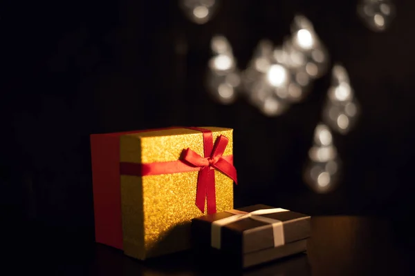 Karanlıkta hediye kutuları ve Noel çelengi ışıkları.