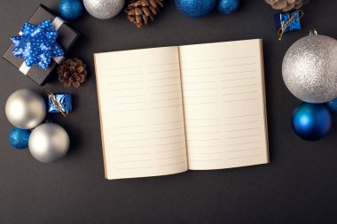 Noel baloları ve külahları arasında açık bir günlük (defter). Yeni yıl hedefleri kavramı.