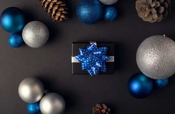 Kleine Geschenkschachtel Mit Schleife Auf Dunklem Hintergrund Zwischen Zapfen Und — Stockfoto