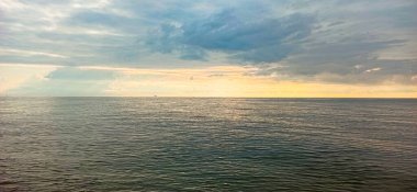 Deniz ufku. Yalnız bir gemi ufuk boyunca sürükleniyor yaz güneşinin yumuşak ışınlarının altında Alçak bulutların arasından kırılıyor