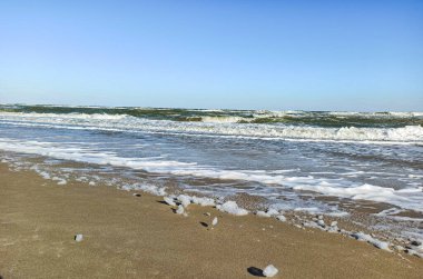 Fırtına denizi. Beyaz fırtınalı dalgalar ıssız bir sonbahar sahilinde uğultu ile uğulduyor sağır edici soğuk rüzgarlar altında kıyıda beyaz köpük parçaları bırakıyor..