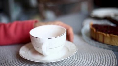 The hands of an old man near a light cup are gesturing
