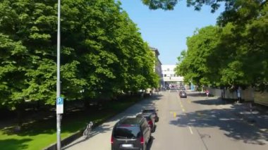 Almanya 'nın Münih şehrinde, güneşli bir yaz gününde çift katlı bir otobüsün tepesinden havadan görülen bir cadde..