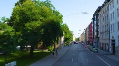 Almanya 'nın Münih şehrinde, güneşli bir yaz gününde çift katlı bir otobüsün tepesinden havadan görülen bir cadde..