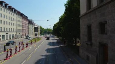 Almanya 'nın Münih şehrinde, güneşli bir yaz gününde çift katlı bir otobüsün tepesinden havadan görülen bir cadde..
