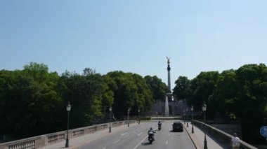 Almanya 'nın Münih şehrinde, güneşli bir yaz gününde çift katlı bir otobüsün tepesinden havadan görülen bir cadde..