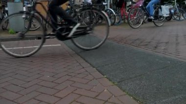 Yazın bulutlu bir günde Amsterdam şehir merkezinde bisikletler geçiyor.