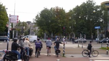 Yazın bulutlu bir günde Amsterdam şehir merkezinde bisikletler geçiyor.