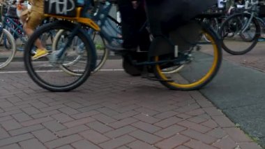 Yazın bulutlu bir günde Amsterdam şehir merkezinde bisikletler geçiyor.