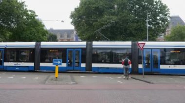 Yazın bulutlu bir günde Amsterdam şehir merkezinde bisikletler geçiyor.