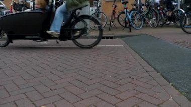 Yazın bulutlu bir günde Amsterdam şehir merkezinde bisikletler geçiyor.