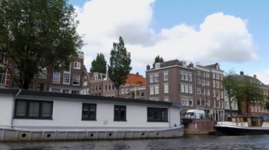 Kanallar boyunca bir tekneye binip güneşli bir günde Amsterdam 'da evler ve binaların yanında dolaşmak.. 