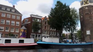 Kanallar boyunca bir tekneye binip güneşli bir günde Amsterdam 'da evler ve binaların yanında dolaşmak.. 