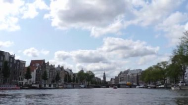 Kanallar boyunca bir tekneye binip güneşli bir günde Amsterdam 'da evler ve binaların yanında dolaşmak.. 