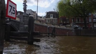 Kanallar boyunca bir tekneye binip güneşli bir günde Amsterdam 'da evler ve binaların yanında dolaşmak.. 