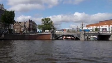 Kanallar boyunca bir tekneye binip güneşli bir günde Amsterdam 'da evler ve binaların yanında dolaşmak.. 