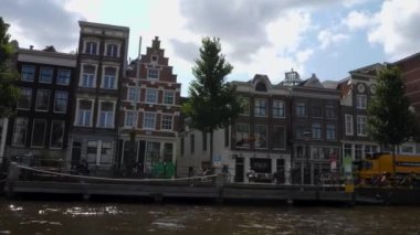 Kanallar boyunca bir tekneye binip güneşli bir günde Amsterdam 'da evler ve binaların yanında dolaşmak.. 