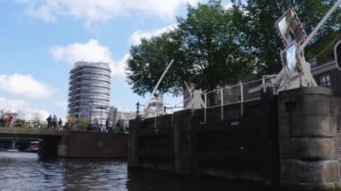 Kanallar boyunca bir tekneye binip güneşli bir günde Amsterdam 'da evler ve binaların yanında dolaşmak.. 