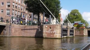 Kanallar boyunca bir tekneye binip güneşli bir günde Amsterdam 'da evler ve binaların yanında dolaşmak.. 