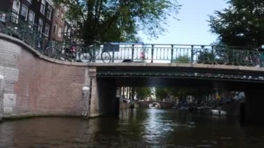 Kanallar boyunca bir tekneye binip güneşli bir günde Amsterdam 'da evler ve binaların yanında dolaşmak.. 