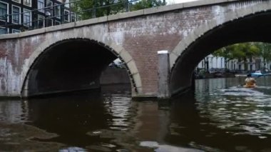 Kanallar boyunca bir tekneye binip güneşli bir günde Amsterdam 'da evler ve binaların yanında dolaşmak.. 