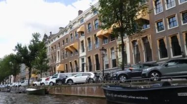 Kanallar boyunca bir tekneye binip güneşli bir günde Amsterdam 'da evler ve binaların yanında dolaşmak.. 