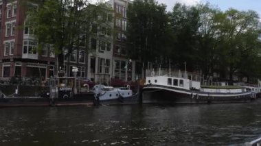 Kanallar boyunca bir tekneye binip güneşli bir günde Amsterdam 'da evler ve binaların yanında dolaşmak.. 