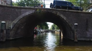 Kanallar boyunca bir tekneye binip güneşli bir günde Amsterdam 'da evler ve binaların yanında dolaşmak.. 