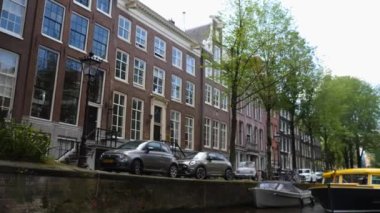 Kanallar boyunca bir tekneye binip güneşli bir günde Amsterdam 'da evler ve binaların yanında dolaşmak.. 