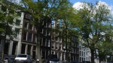 Kanallar boyunca bir tekneye binip güneşli bir günde Amsterdam 'da evler ve binaların yanında dolaşmak.. 