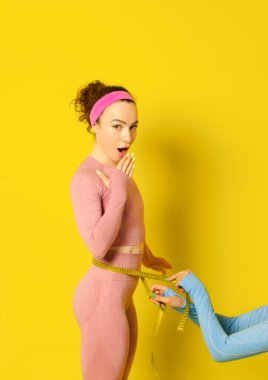 Spor giyimli güzel, ince bir kadın göbeğini ya da belini bir bantla ölçüyor. Diyet ve spor konsepti