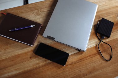 Ahşap masadaki akıllı telefon akıllı telefon, günlük, dizüstü bilgisayar, sabit disk ve kalem.