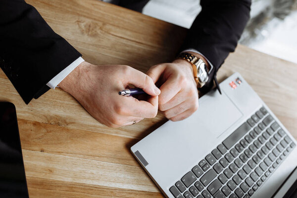 man's hands with a pen on the table with notepad