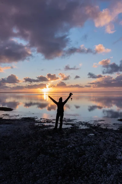Gölde gün doğumunda bir kadının silueti.