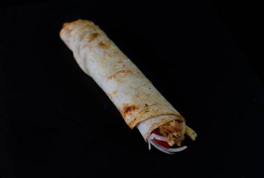 Chicken doner kebab in lavash bread on black background. Traditional Turkish cuisine delicacies