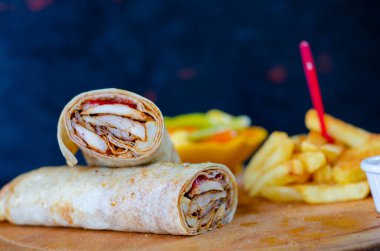 Doner kebab in lavash bread. Close-up delicious chicken doner burrito on black background. Potato chips. selective focus