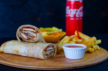 Doner kebab in lavash bread. Close-up delicious chicken doner burrito on black background. Potato chips. selective focus