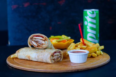 Doner kebab in lavash bread. Close-up delicious chicken doner burrito on black background. Potato chips. selective focus