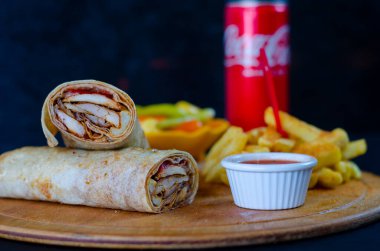 Doner kebab in lavash bread. Close-up delicious chicken doner burrito on black background. Potato chips. selective focus