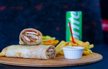 Doner kebab in lavash bread. Close-up delicious chicken doner burrito on black background. Potato chips. selective focus