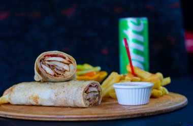 Doner kebab in lavash bread. Close-up delicious chicken doner burrito on black background. Potato chips. selective focus