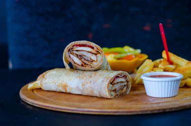 Doner kebab in lavash bread. Close-up delicious chicken doner burrito on black background. Potato chips. selective focus