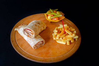 Doner kebab in lavash bread. Close-up delicious chicken doner burrito on black background. Potato chips. selective focus
