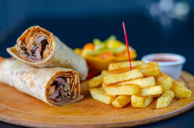 Doner kebab in lavash bread. Close-up delicious chicken doner burrito on black background. Potato chips. selective focus